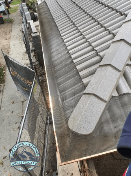 A tile roof with copper gutters featuring a gutter guard installation, effectively preventing debris buildup and ensuring optimal protection.