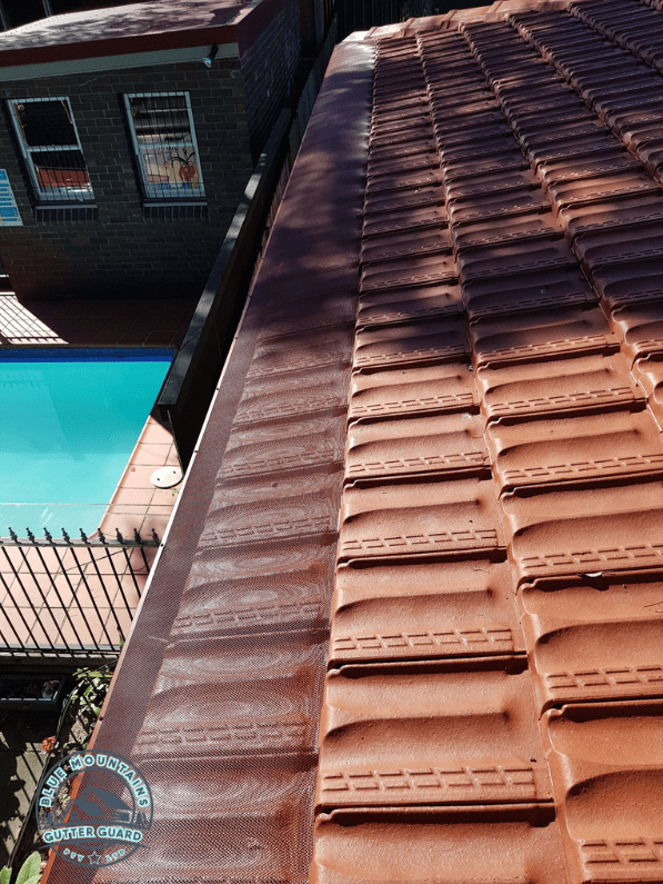 A tile roof with a newly installed gutter guard, providing enhanced protection against leaves and debris.