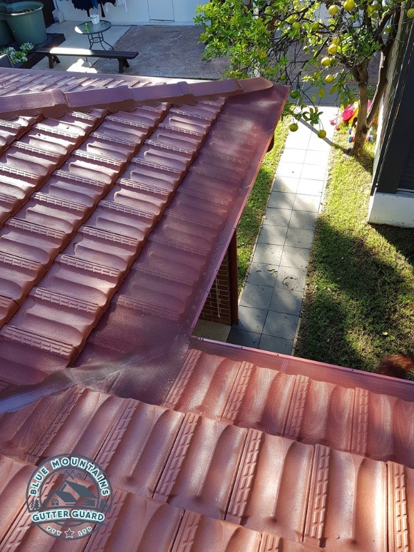 A tile roof and valley featuring a gutter guard installation, effectively preventing debris buildup and ensuring optimal protection.