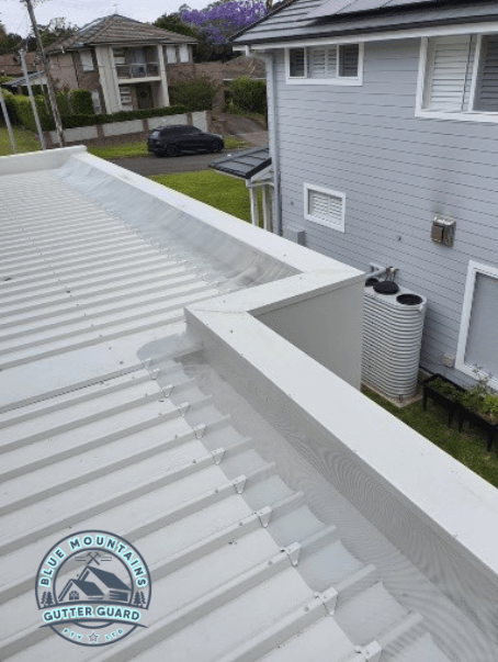 A close-up view of a gutter guard installed on a box gutter, showcasing its effectiveness in preventing debris buildup.